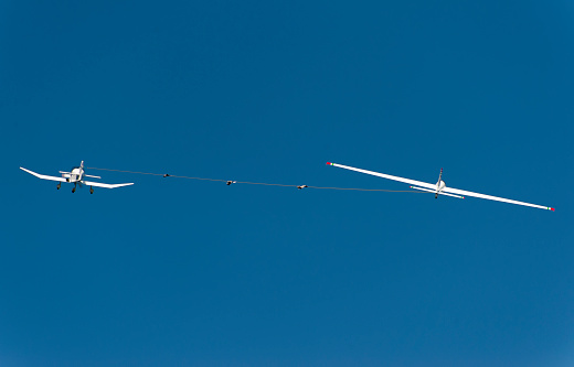 A powered aircraft pulls a glider into the air during take-off