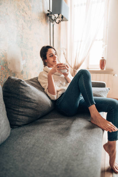istock pretty woman drinking an hot tea on the couch 1347853836