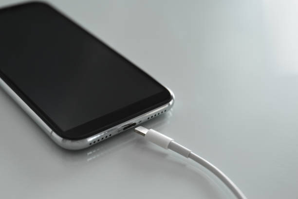 istock Mobile phone and charging cable on white table, closeup 1347853927