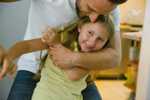 istock Father and daughter laugh and play together through the living room 1347856468