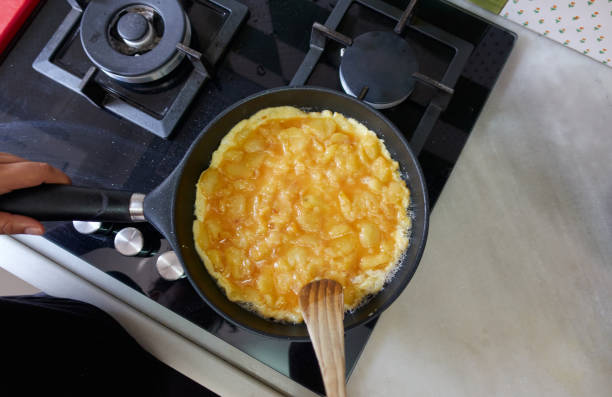 spanisches omelett in einer pfanne kochen, bevor es umgedreht wird - spanisches omelett stock-fotos und bilder