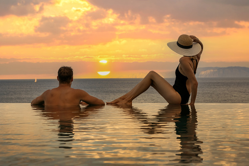 honeymoon vacation - couple enjoying romantic sunset in infinity pool at luxury resort