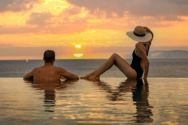 honeymoon vacation - couple enjoying romantic sunset in infinity pool at luxury resort stock photo