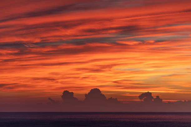 Cala Gonone - Italy - 09/29/2021\nThe sun has not yet risen but the cloudy sky is already lit up in vivid red. At the horizon a strip of dark clouds far away