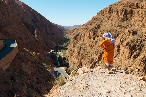A person in traditional clothing looks at the scenery in the Dades Gorge in Morocco, Africa