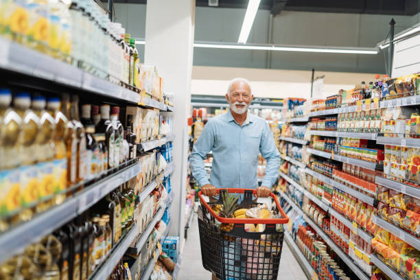 Retired man buying groceries People buying groceries in supermarket consumer confidence photos stock pictures, royalty-free photos & images