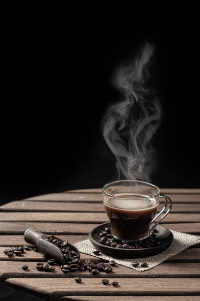 istock Hot steaming coffee in a glass cup and coffee bean on black background. Vertical format. 1347863886