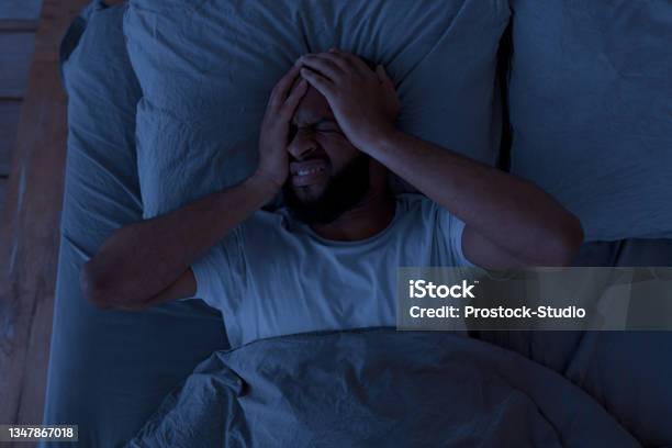 Black Man Suffering From Headache Or Migraine At Night Stock Photo - Download Image Now