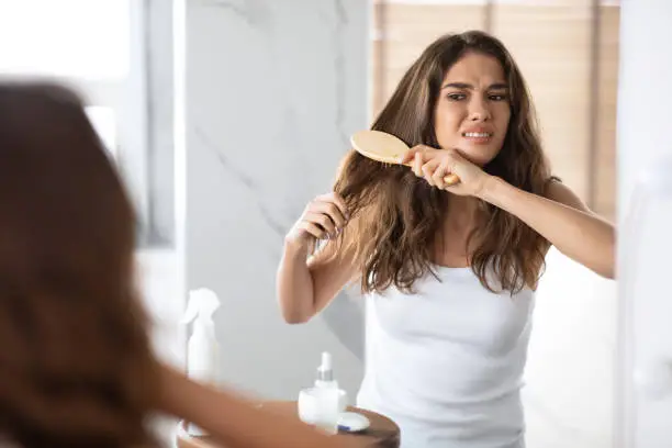 Photo of Desperate Woman Brushing Dry Tangled Hair With Hairbrush At Home