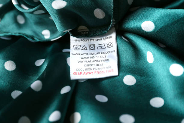 étiquette de vêtement avec instructions d’entretien et informations sur le contenu du vêtement à pois vert, gros plan - polyester photos et images de collection