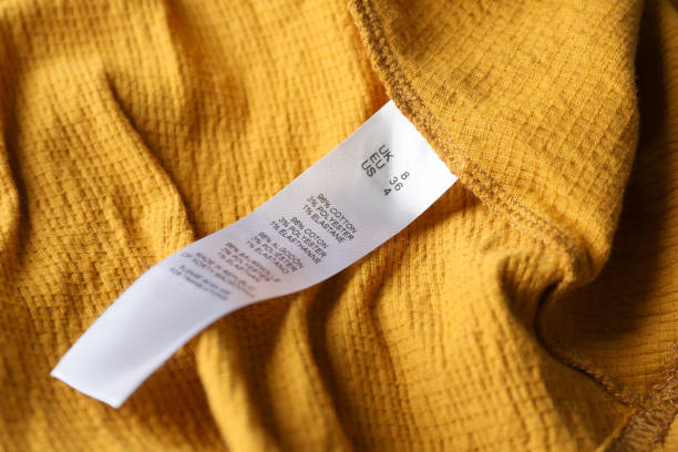 istock Clothing label with size and content information on yellow garment, closeup 1347868562