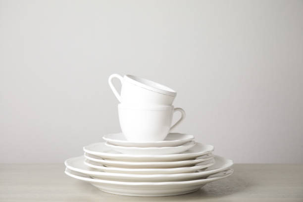 istock Stack of clean plates and cups on table against white background 1347868737