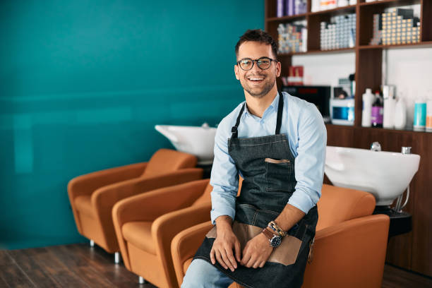 happy male hairdresser working at hair salon and looking at camera. - family business stockfoto's en -beelden