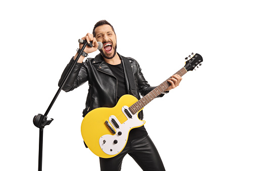 Male singer with a microphone and an electric guitar singing loud isolated on white background