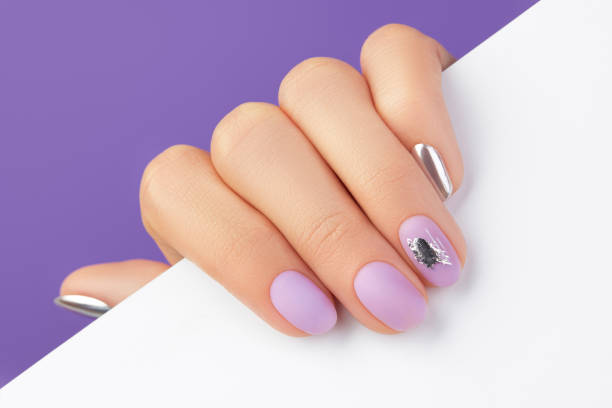 Close up womans hand with matte lavender nail design on purple background Close up womans hand with matte lavender nail design on purple background. Manicure, pedicure beauty salon concept fall nail art stock pictures, royalty-free photos & images