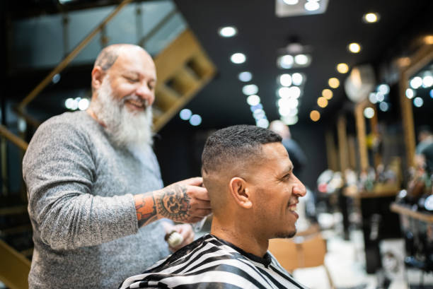 parrucchiere che taglia i capelli di un giovane al barbiere - negozio del barbiere foto e immagini stock