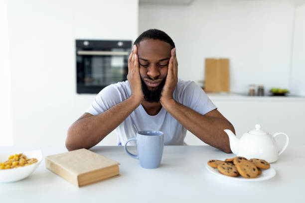 Black man suffering from insomnia sitting at desk