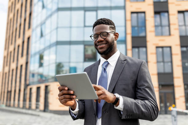 istock Confident black businessman with tablet outdoors. Insuranse agent browsing news on digital device, walking outdoors 1347878367