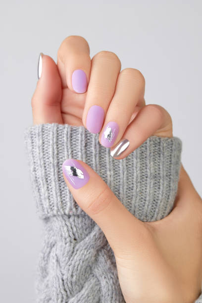 Close up womans hands with matte lavender and silver nails in sweater Close up womans hands with matte lavender and silver nails in sweater. Manicure, pedicure design trends fall nail art stock pictures, royalty-free photos & images