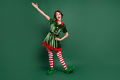 Full length body size view of attractive cheerful funny girl elf having fun celebratory isolated over green color background