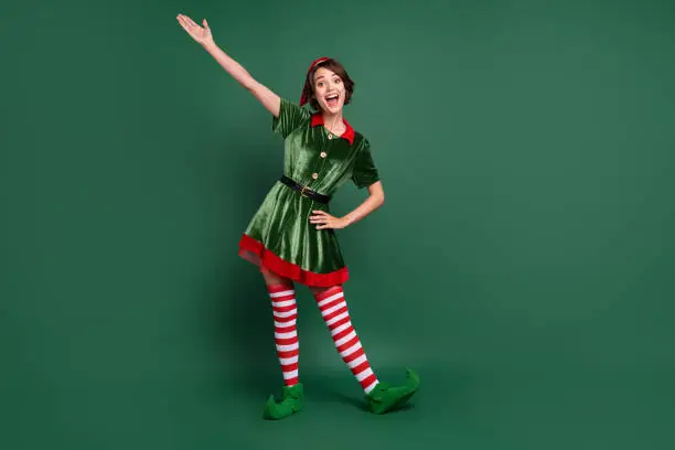Full length body size view of attractive cheerful funny girl elf having fun celebratory isolated over green color background