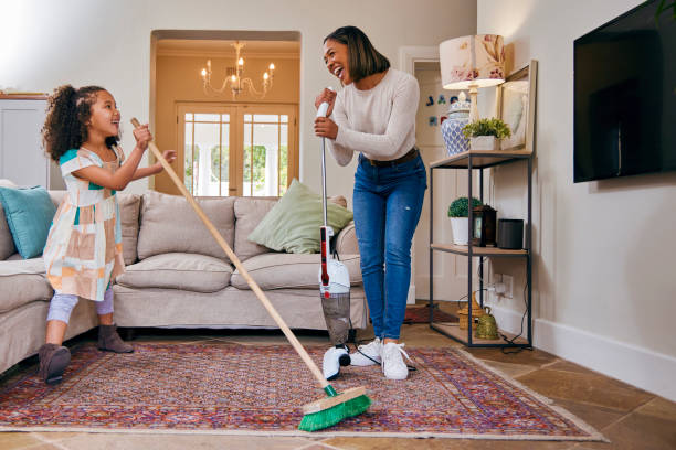 shot of a mother and daughter having fun while cleaning the living room - spring cleaning women cleaning dancing imagens e fotografias de stock