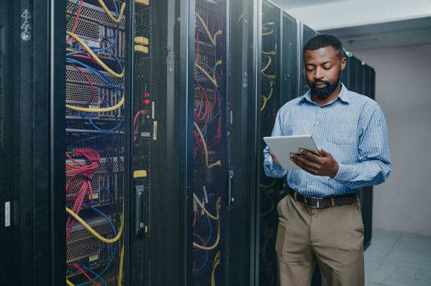 istock Shot of a young man using a digital tablet while working in a server room 1347879793
