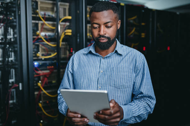 istock Shot of a young man using a digital tablet while working in a server room 1347879851