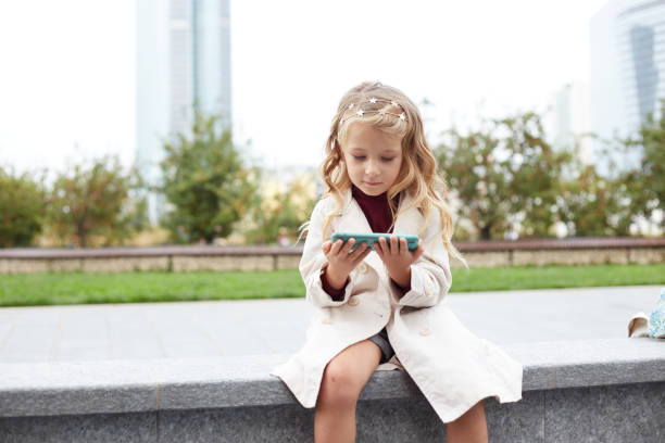 istock Funny child with long hair holding a mobile 1347879935