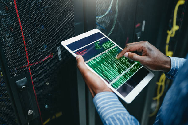 istock Shot of a young man using a digital tablet while working in a server room 1347879962