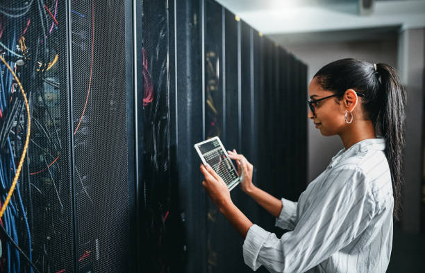 Shot of a young woman using a digital tablet while working in a server room Every machine has to work properly encryption stock pictures, royalty-free photos & images