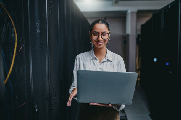 istock Portrait of a young woman using a laptop while working in a server room 1347880007