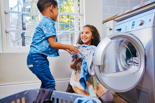 istock Shot of a brother and sister loading laundry into a washing machine 1347880083