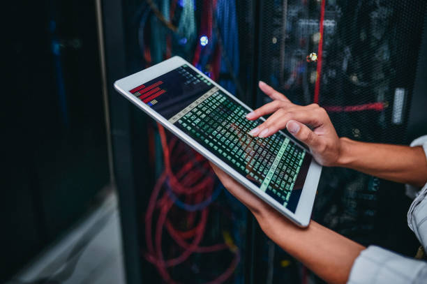 istock Shot of a young woman using a digital tablet while working in a server room 1347880093