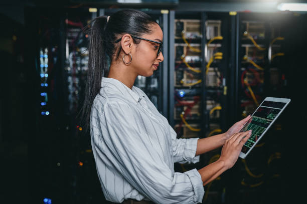 istock Shot of a young woman using a digital tablet while working in a server room 1347880106