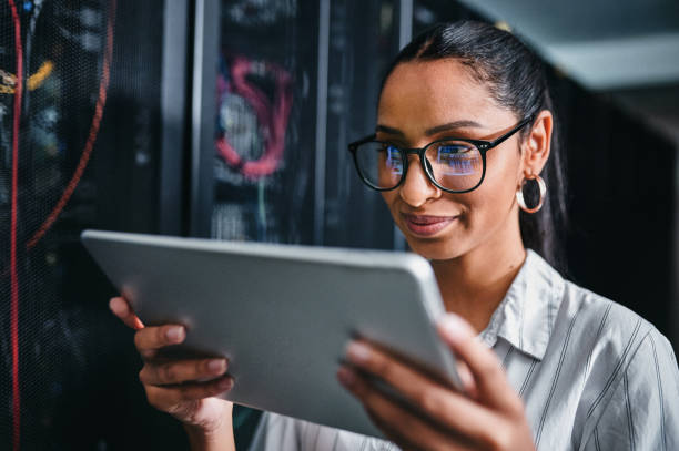 istock Shot of a young woman using a digital tablet while working in a server room 1347880118