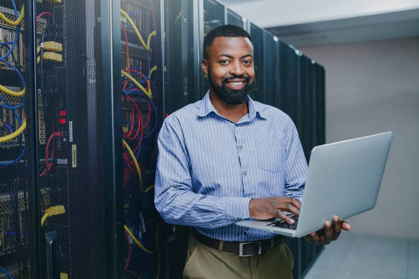 istock Portrait of a young man using a laptop while working in a server room 1347880316