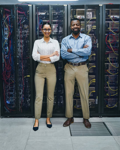 istock Portrait of two young technicians standing with their arms crossed while working in a server room 1347880332