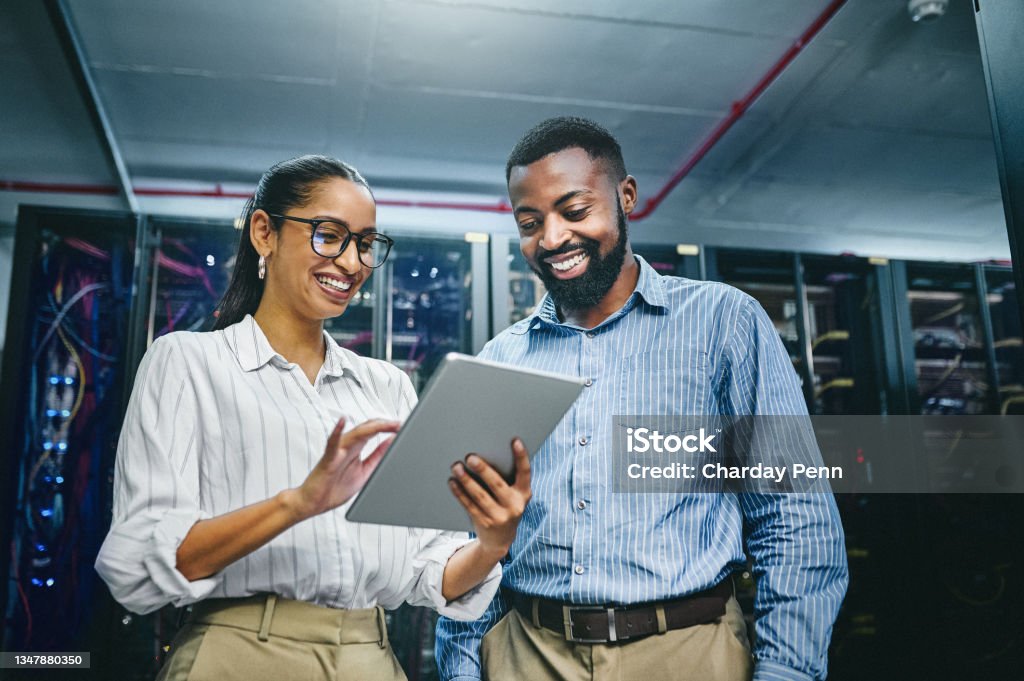 Shot of two young technicians using a digital tablet while working in a server room We can optimise this Technology Stock Photo