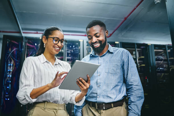 Shot of two young technicians using a digital tablet while working in a server room We can optimise this cloud computing stock pictures, royalty-free photos & images