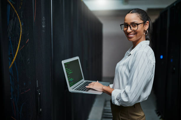 istock Portrait of a young woman using a laptop while working in a server room 1347880361