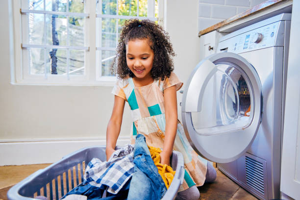 istock Shot of a young child loading laundry into a washing machine 1347881486