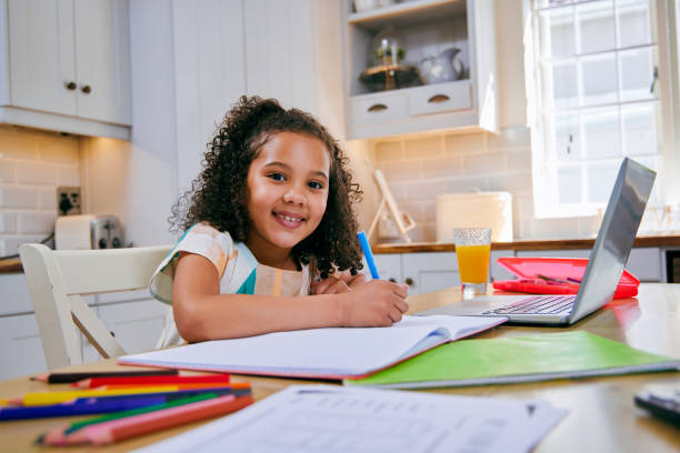 istock Shot of a young girl completing her homework in her kitchen using a laptop 1347882613