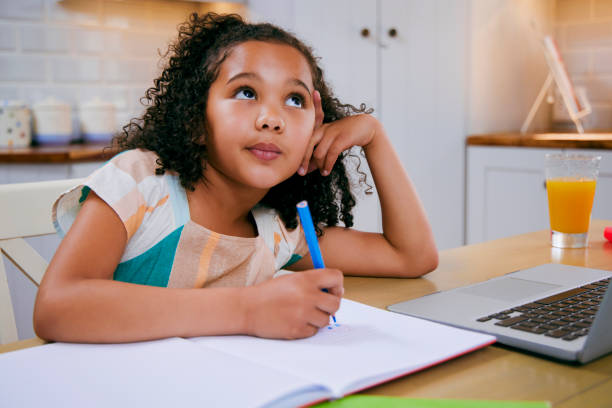 shot of a little girl daydreaming while doing her homework - child thinking writing little girls imagens e fotografias de stock