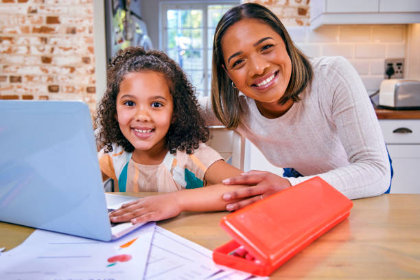 photo d’une mère aidant sa fille dans ses travaux scolaires - home schooling photos et images de collection