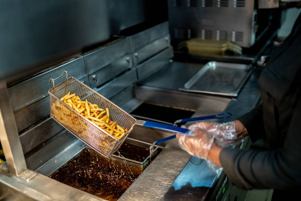 Female hands holding a frying pan with french fries at a commercial kitchen Female hands holding a frying pan with french fries at a commercial kitchen fried stock pictures, royalty-free photos & images