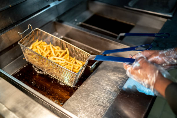Female hands holding a frying pan with french fries at a commercial kitchen