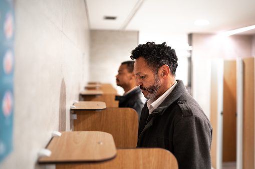 Two men urinating at a public restroom