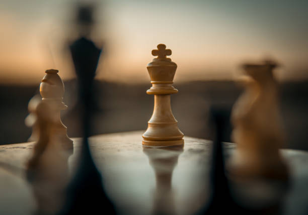 Chess game on the chessboard with selective focus on the king under a sunset