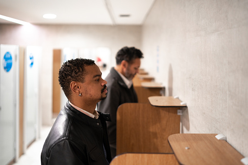 Two men urinating at a public restroom